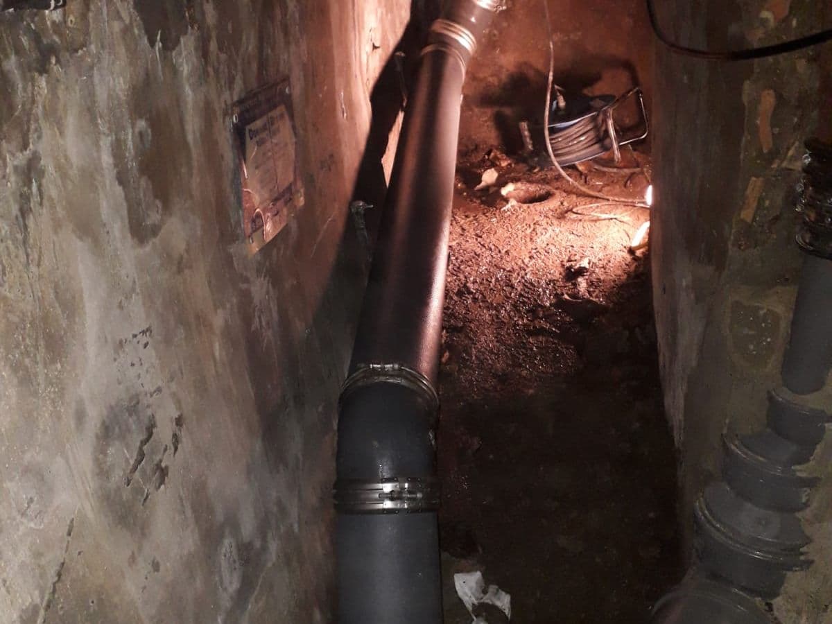 Collecteur en fonte remplacé par des canalisations neuves dans un passage en sous-sol
